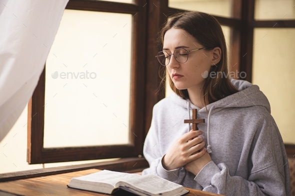 The girl reading the Bible and prays. Prayer. Faith and religion. Believing girl praying. Bible.
