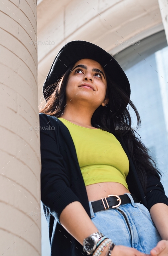 Full body portrait of stylish young girl in fedora hat leaning on old building column Stock