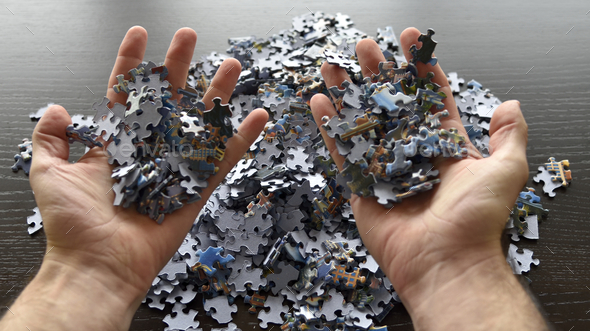 Point of view personal perspective hands with thousands of jigsaw puzzle pieces