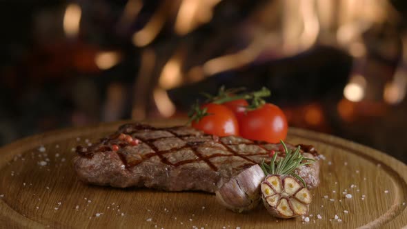 Rotating Grilled Beef Steak on Fireplace Background