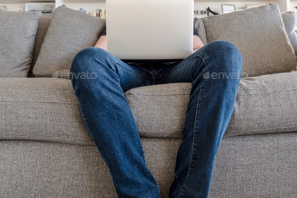 Man with laptop on sofa working from home - Stock Photo - Images
