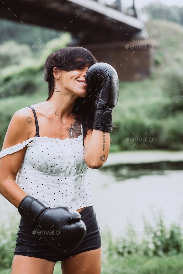 Beautiful sportswoman in boxing gloves training boxing. Strong woman practicing boxing outdoors.