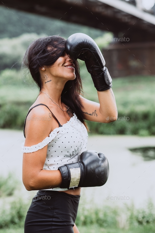 Beautiful sportswoman in boxing gloves training boxing. Strong woman practicing boxing outdoors