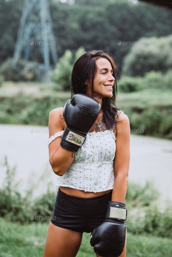 Beautiful sportswoman in boxing gloves training boxing. Strong woman practicing boxing outdoors