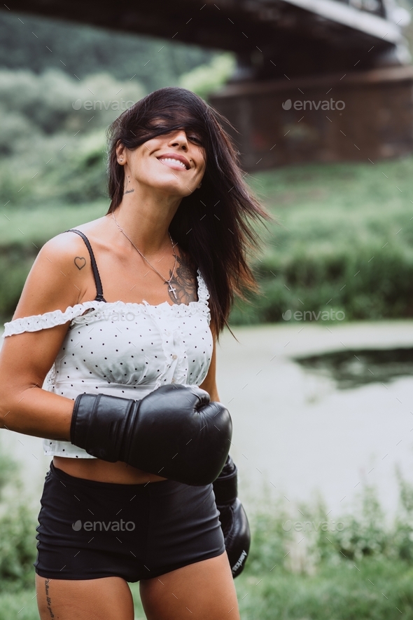 Beautiful sportswoman in boxing gloves training boxing. Strong woman practicing boxing outdoors.