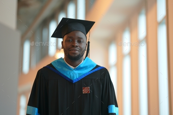 new graduates. Afro male graduate is smiling against the background of university. Concept of educat