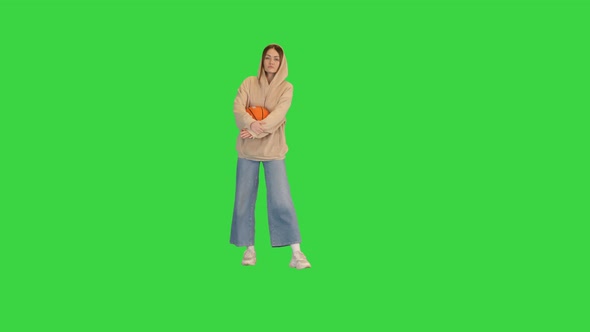 Young Sporty Girl Dancing in a Casual Way with Basketball Ball in Hands on a Green Screen Chroma Key