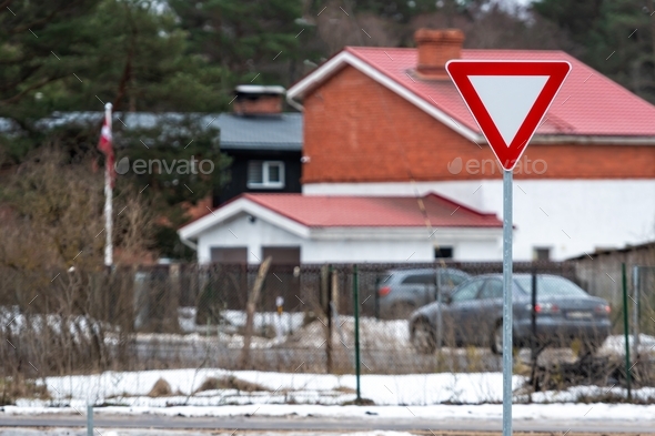 road sign GIVE WAY against the background of a defocused residential area, close-up - Stock Photo - Images