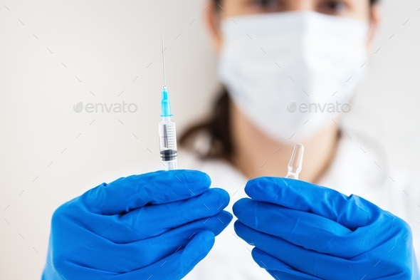 A doctor with a syringe and a vaccine in his hands. Vaccination against influenza and viruses.