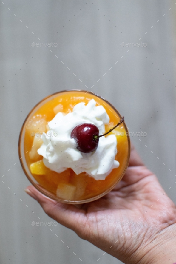 Peach dessert with whipped cream and cherry on top