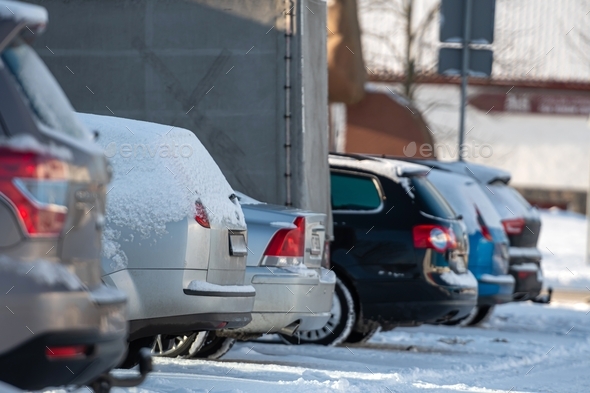 row of different cars parked in the outdoor parking lot on a snowy winter day