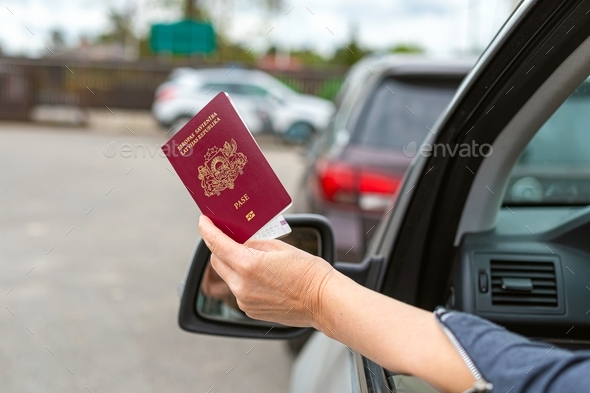 women hand through car window giving passport for customs control, rear view, close-up