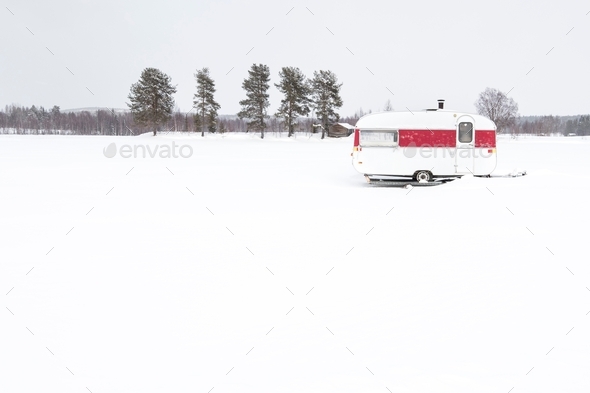 White and red old holiday ice fishing retro caravan in Sweden against the winter snow background sel