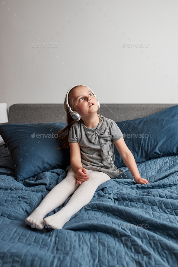 Little girl singing holding headphones cord imitating herself a real singer. Child having fun