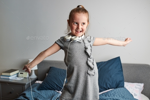 Little girl singing holding headphones cord imitating herself a real singer