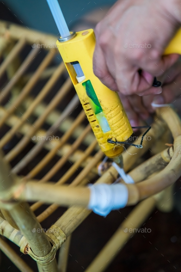 using glue gun to repair the rattan chair Stock Photo by ellinnur