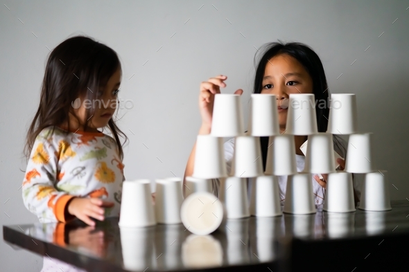 children playing white paper cups stacking at home Stock Photo by ellinnur