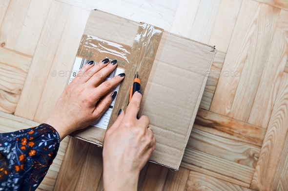 Woman opening parcel online order. Unpacking box with ordered items. Online shopper opening box