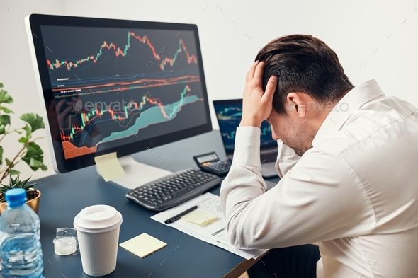 Worried businessman looking at charts stressed by news from stock market. Investor lost money online