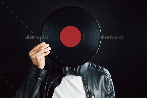 Music vinyl record. Man holding black vinyl record over face. Vintage music style. Rock style. Black