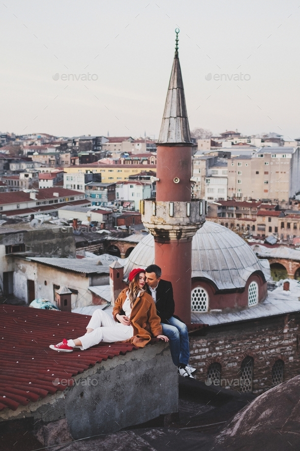 Couple in love sitting  on roof with view of evening Istanbul. Casual style, autumn look, red beret  - Stock Photo - Images
