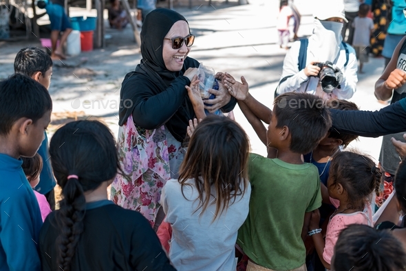 woman volunteer in hijab distributing items to the Bajau Laut community ...