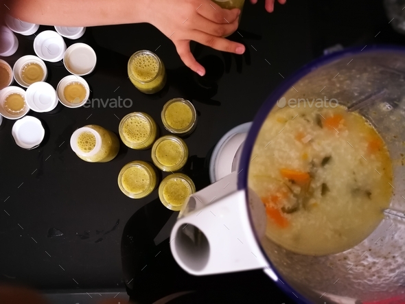 top view of prepping baby food, rice porridge with vegetables in the blender into small containers