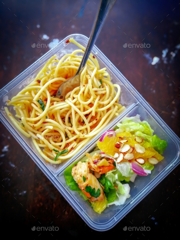 Pasta in a take away box, lunch box on a wooden table.