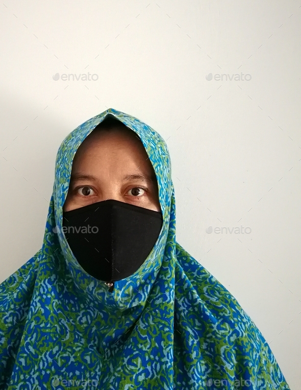 muslim Asian woman wearing face mask against white wall