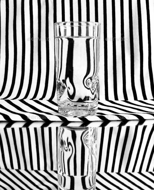 Glass of water abstract with B&W lines reflected on a mirror giving an optical illusion sensation.