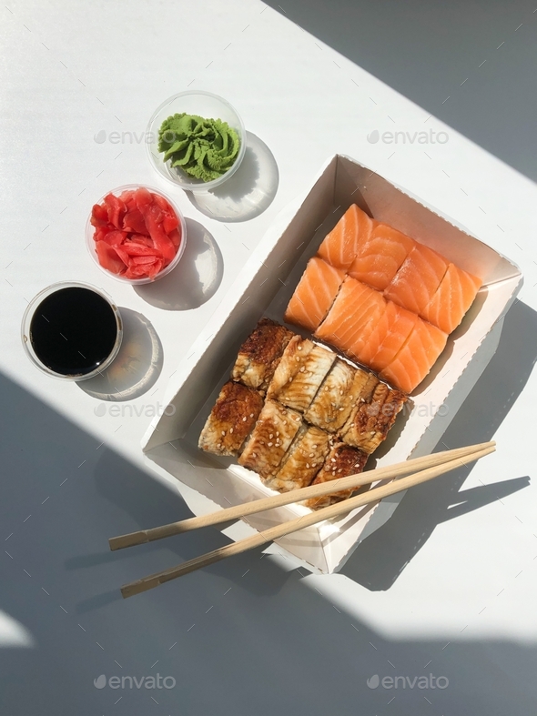 Flat lay food with salmon and unagi sushi and ginger, soy sauce, wasabi