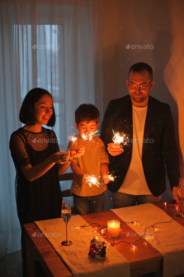 Happy family celebrating new year eve at home with sparklers and