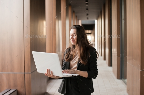 Student girl dressed in black outfit with laptop studying at university campus
