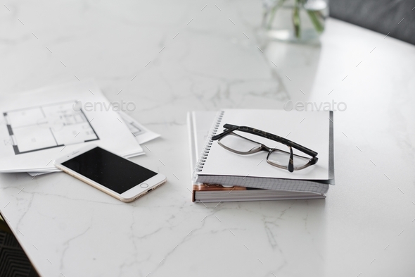 Mobile phone, notebook, books, reading glasses on the marble table - work aesthetics lifestyle