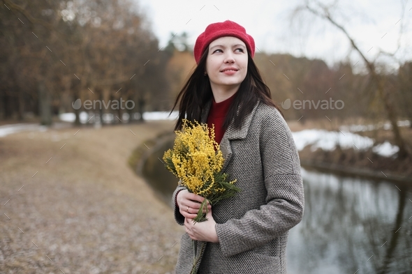 beautiful portrait of a young woman with mimosa flowers outdoors