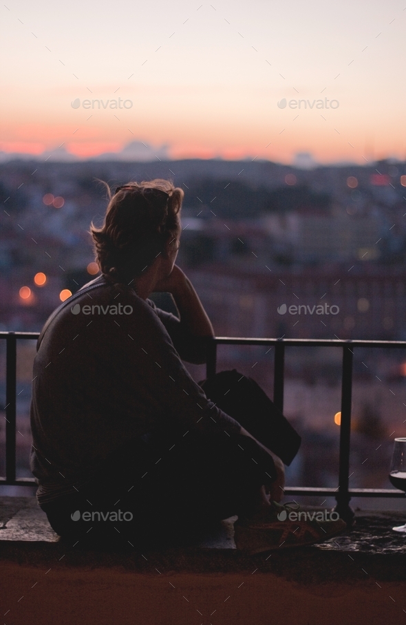 Young woman watching sunset, deep in thought, reflecting, people in the city, silhouette