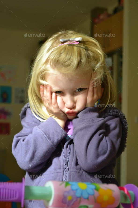 Toddler girl squeezing cheeks and pulling funny face, children, purple