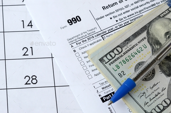 Form 990 Return of organization exempt from income tax and blue pen with dollar bills lies on office - Stock Photo - Images