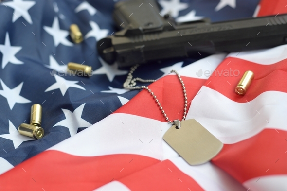 Army Dog tag token with 9mm bullets and pistol lie on folded United States flag