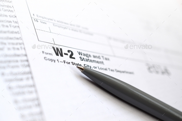 The pen lies on the tax form W-2 Wage and Tax Statement. The time to pay taxes