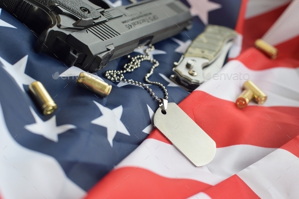 Army Dog tag token with 9mm bullets and pistol lie on folded United States flag