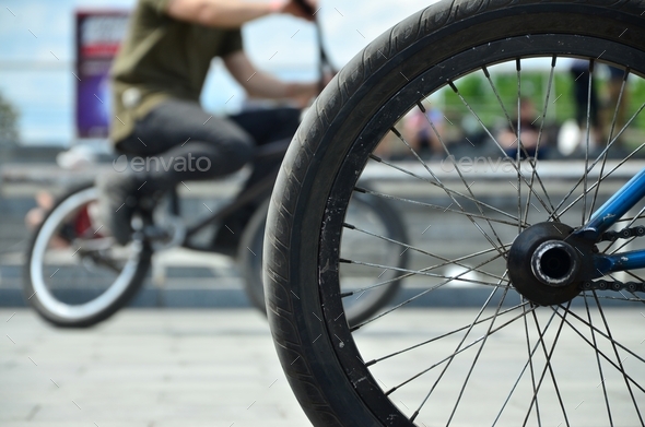 A BMX bike wheel against the backdrop of a blurred street with cycling riders