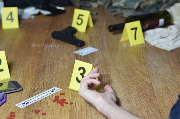 Hand of dead victim surrounded by evidence markers and objects on floor of residential apartment