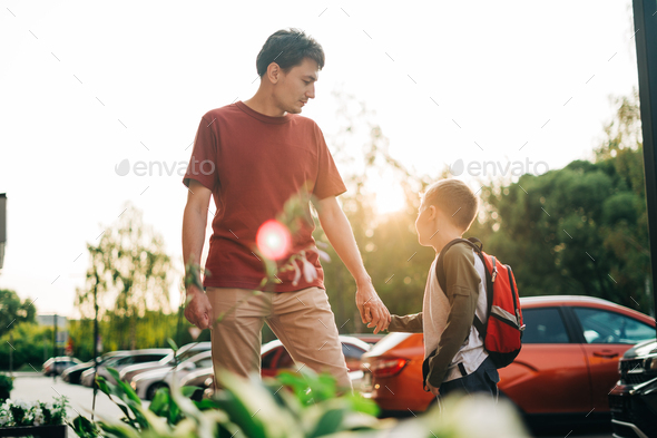 Happy father and kid son going to classes. Parent take child boy to school in first grade. Pupil of