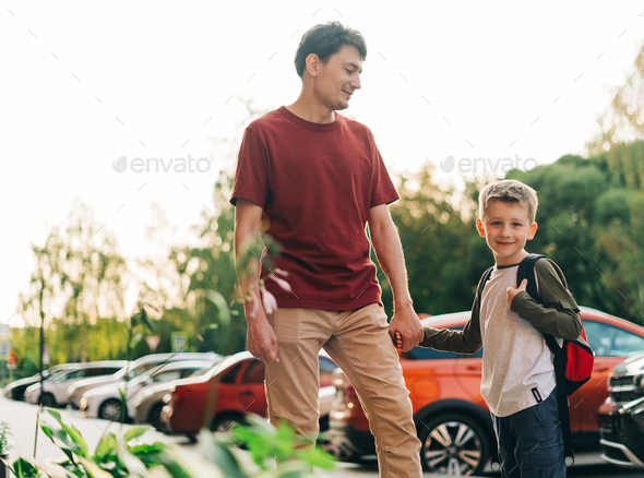 Happy father and kid son going to classes. Parent take child boy to school in first grade. Pupil of