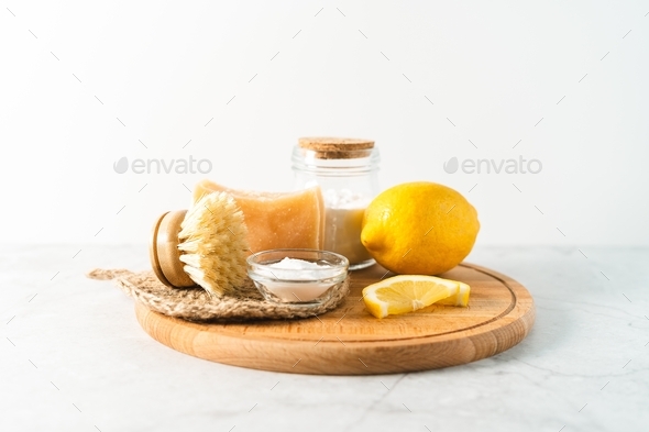 Eco friendly natural cleaners, jar with baking soda, dish brush, lemon, soap on white marble table