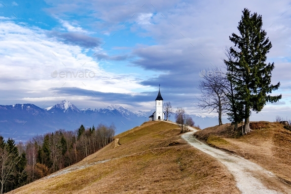 Beautiful mountain landscape with empty path leading to church on top of hill.