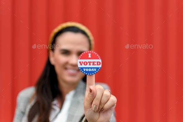 Selective focus image of woman smiling and holding voting sticker with i voted today text.