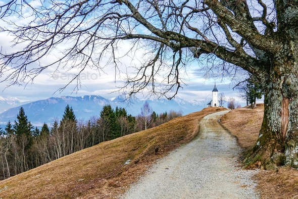 Beautiful mountain landscape with empty path leading to church on top of hill.