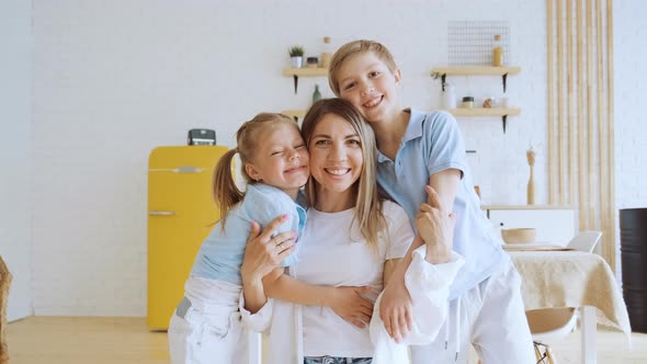 Portrait of Happy Mother with Children Small Son and Daughter Hugging Their Mom